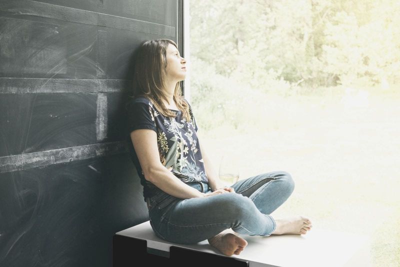 vrouw met een glas wijn zittend bij het raam op een luie zomer