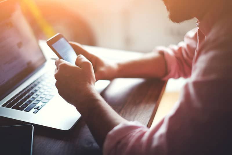 Mann, der am Telefon tippt