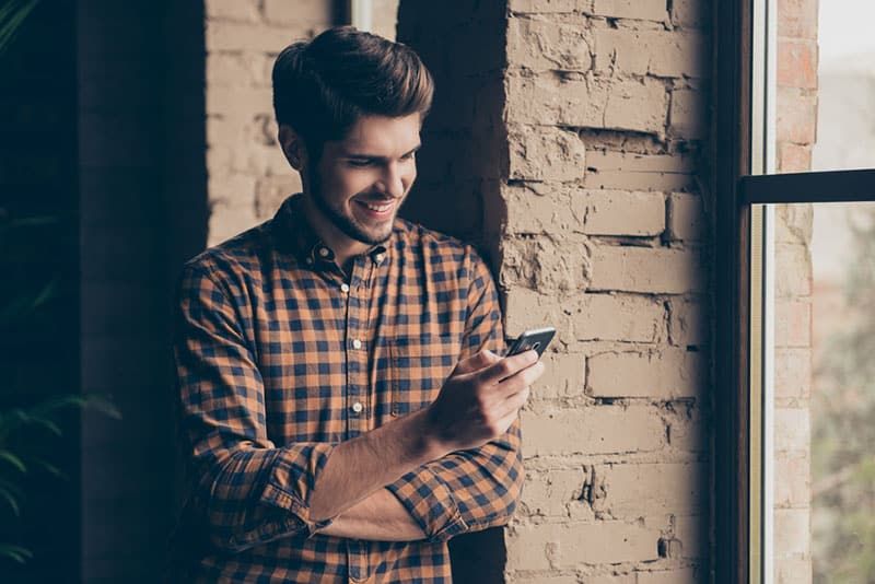 gutaussehender mann, der am telefon tippt