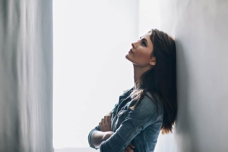 traurige Frau, die an der Wand steht