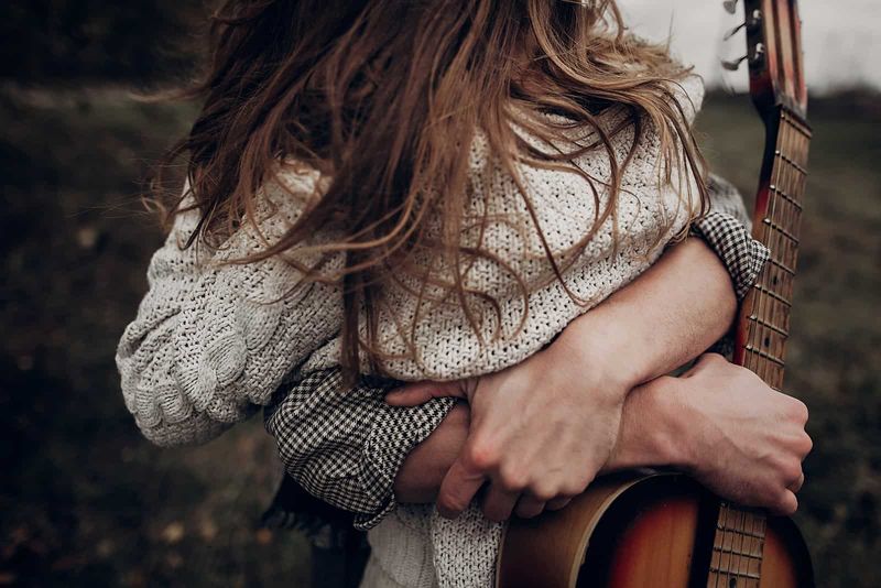 mężczyzna przytulający kobietę trzymając gitarę