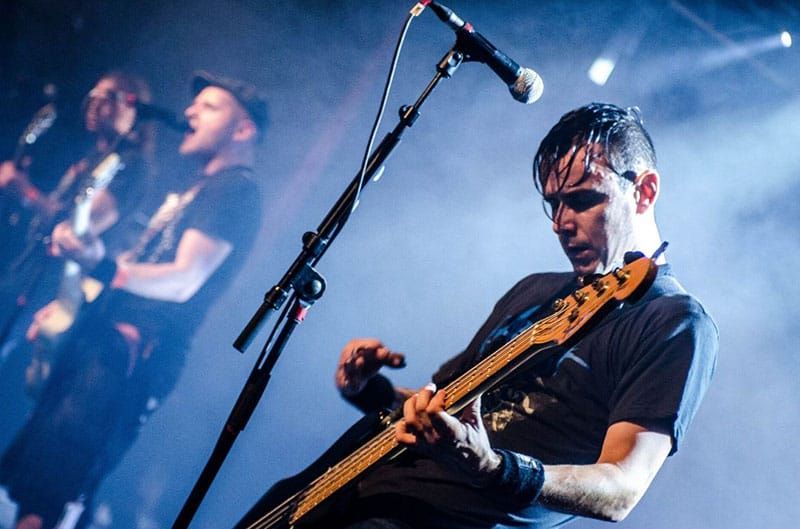 rocker gut memetik gitar di panggung dan anggota tim rock lainnya