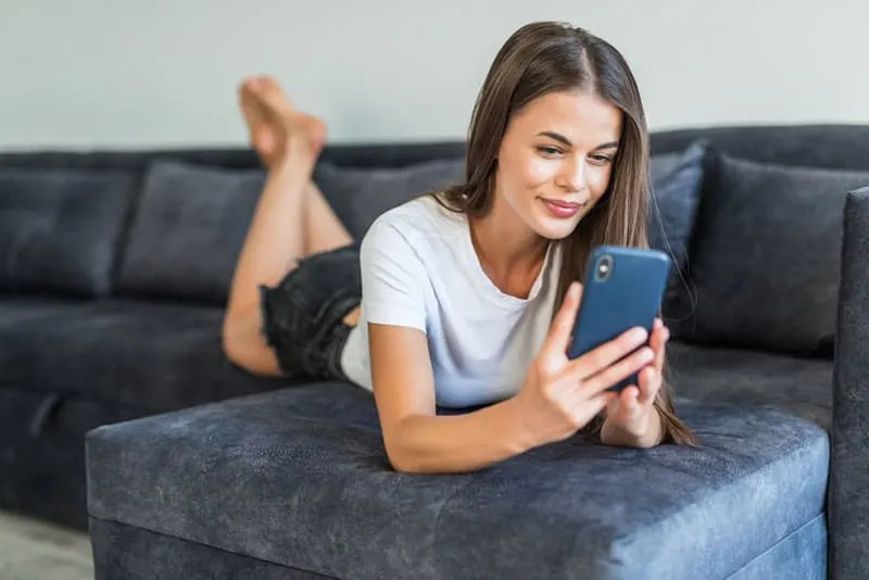 dona jove somrient mirant el telèfon