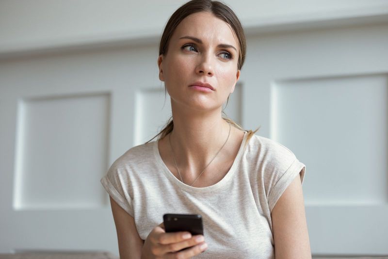 متأمل امرأة الرسائل النصية على الهاتف الذكي داخل المنزل