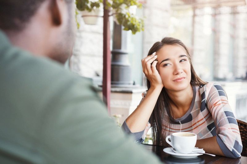 امرأة تشعر بالملل تنظر إلى الرجل بنظرة رتيبة على وجهها في موعد في أحد المقاهي