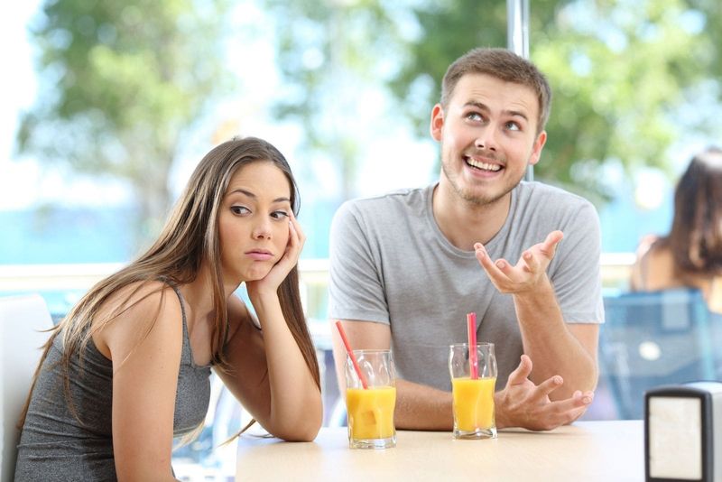 امرأة بالملل تعود إلى رجل ثرثارة في الهواء الطلق يشرب عصير الفاكهة