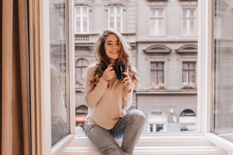 la dona està asseguda a la finestra prenent cafè