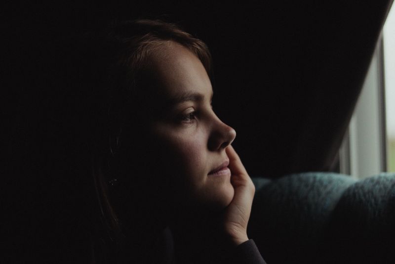 vrouw die haar gezicht aanraakt terwijl ze binnen zit