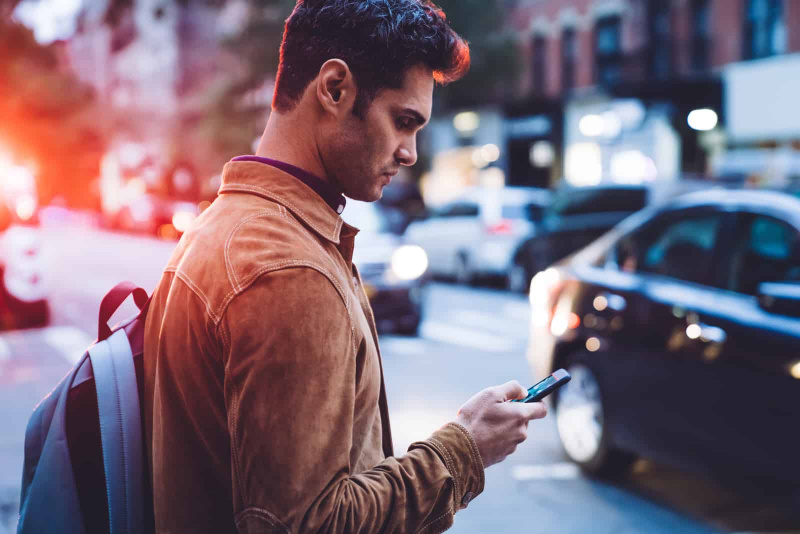 Mann, der mitten auf der Straße eine SMS auf sein Telefon schreibt