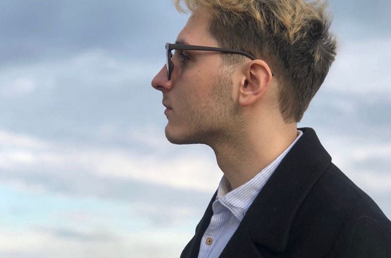 Seitenansicht eines Mannes mit Brille im formellen Anzug, der sich im Freien aufhält