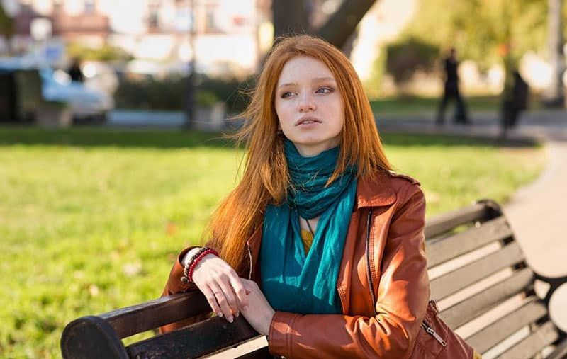 nachdenklich aussehende Frau, die auf der Bank im Park sitzt
