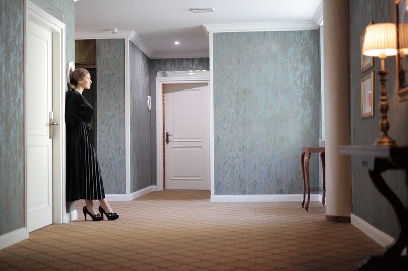 Frau in der Nähe der Tür, die schwarzes Kleid und Schuhe trägt