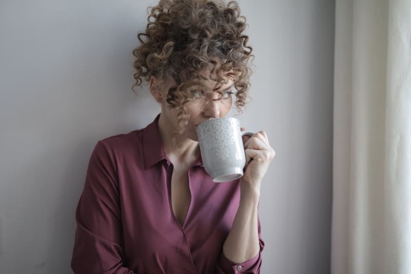 vrouw in roze shirt koffie drinken binnen