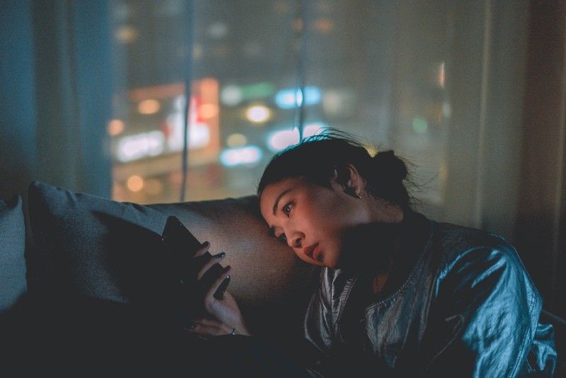 vrouw die telefoon gebruikt terwijl ze op de bank zit