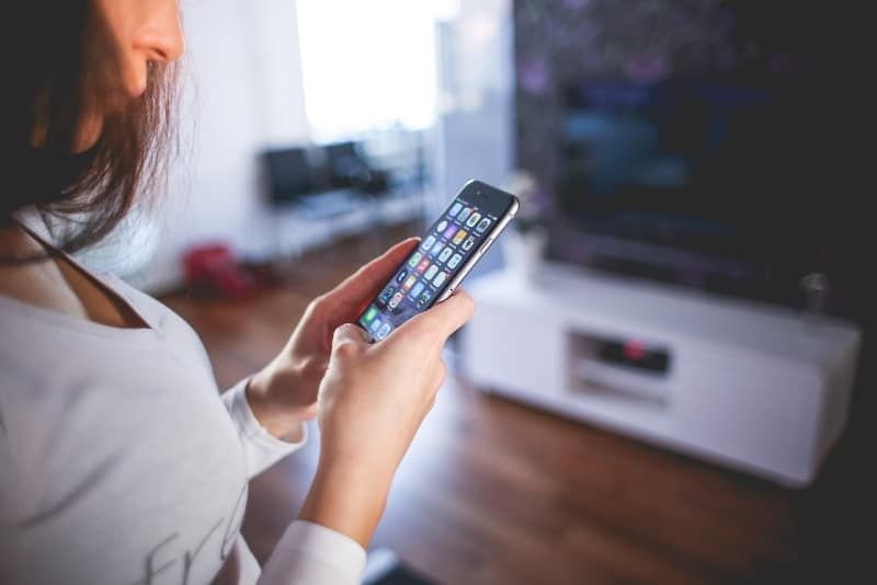 vrouw die een wit overhemd met v-hals draagt ​​en naar de telefoon kijkt