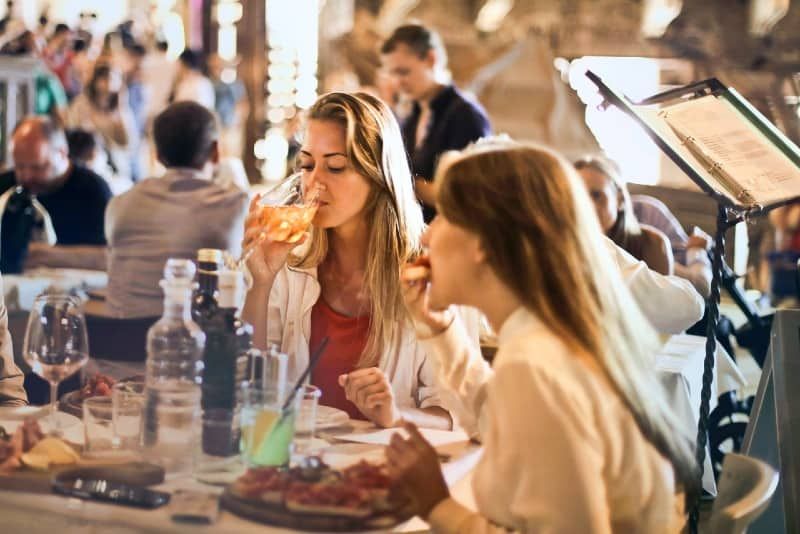 vrouw die wijn drinkt terwijl ze met een andere vrouw aan tafel zit