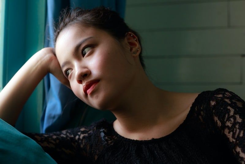 vrouw leunt haar hoofd tegen haar hand terwijl ze binnen zit