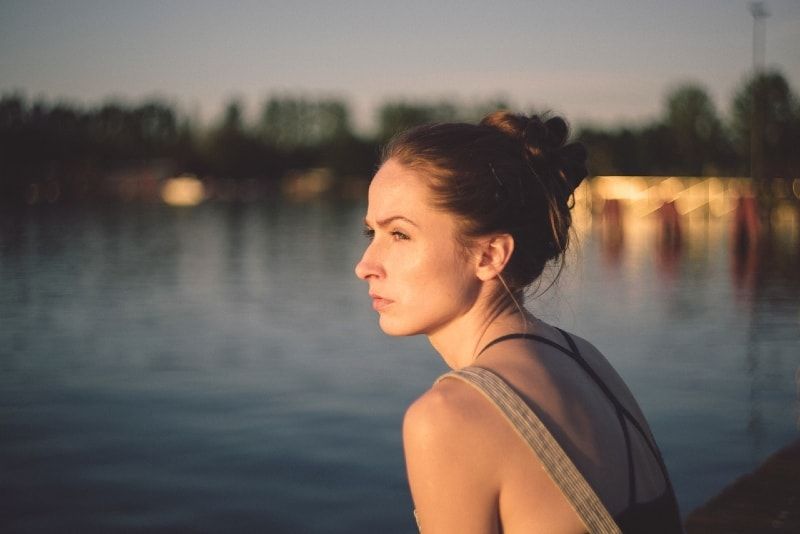 vrouw met haarknot zit in de buurt van water