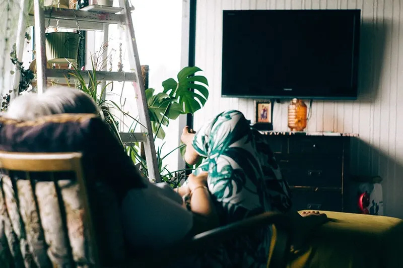   wanita duduk di kursi berlengan sambil menonton TV dimatikan