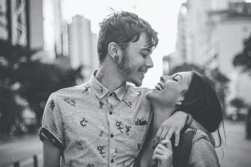 người đàn ông và phụ nữ mỉm cười ôm nhau khi đứng ngoài trời