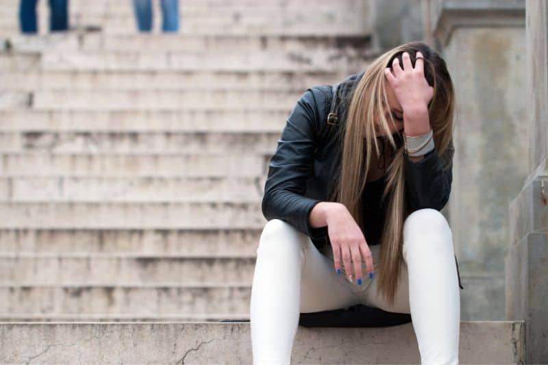 Trauriges junges Mädchen sitzt auf der Treppe des Campus