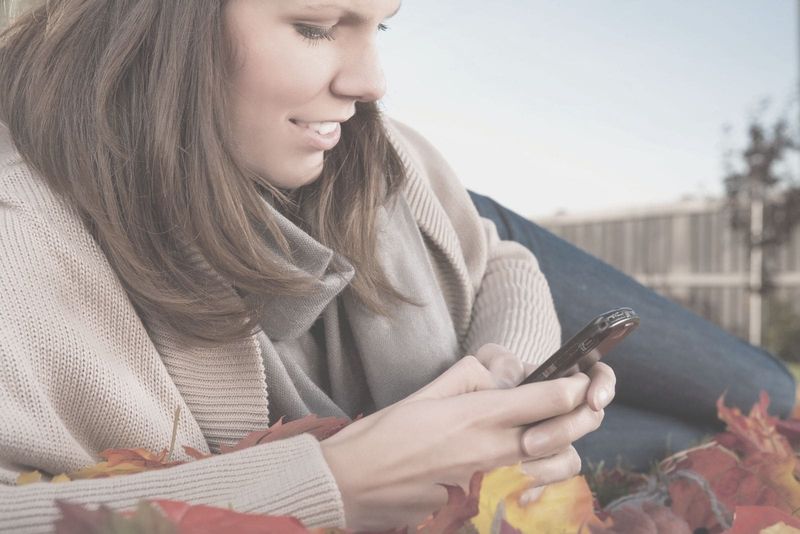 Schöne Frau, die im Sitzen auf dem Smartphone in den sozialen Medien surft