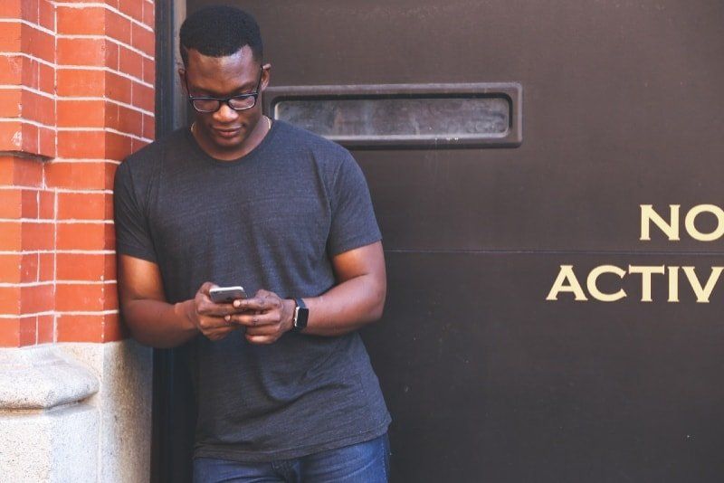 Mann im grauen T-Shirt mit Smartphone