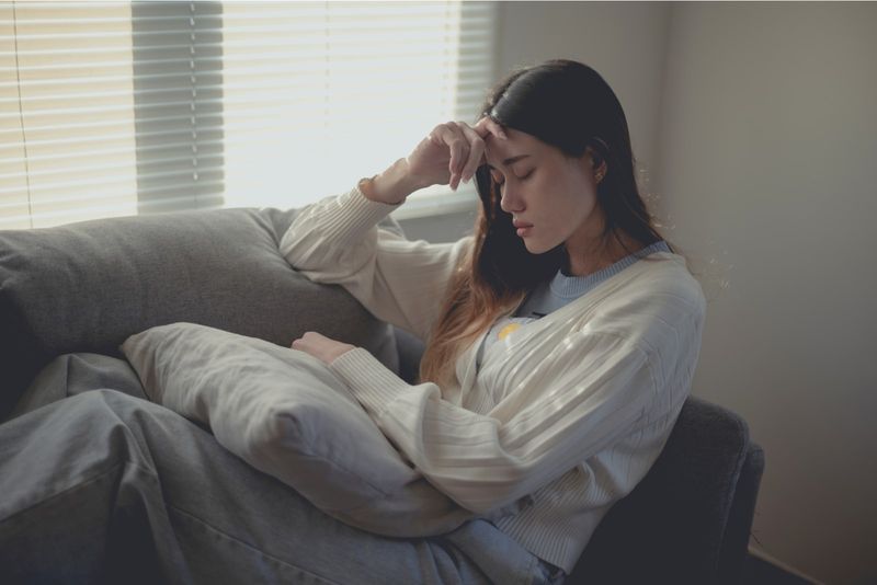 Ein trauriges asiatisches Mädchen sitzt auf der Couch und denkt nach