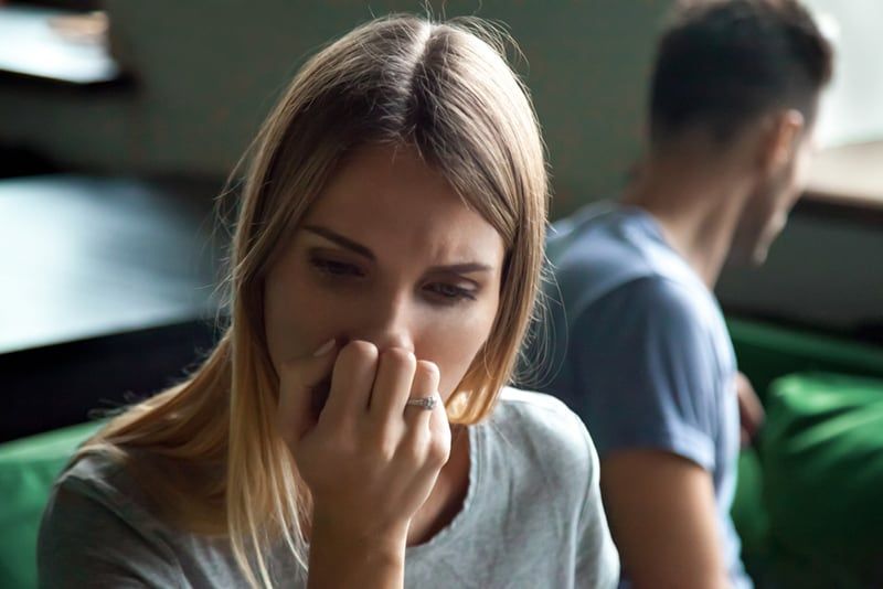 sfrustrowana kobieta odwracająca głowę od swojego chłopaka siedzącego obok niej na kanapie