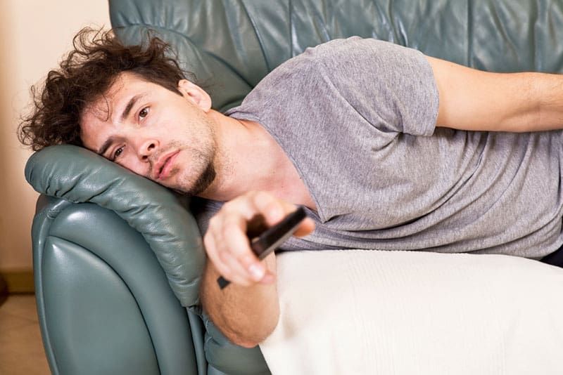 رجل كسول وضع على الأريكة يشاهد التلفاز