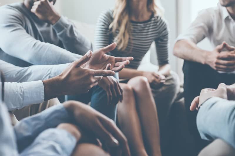grupa ludzi rozmawiająca siedząc w pomieszczeniu