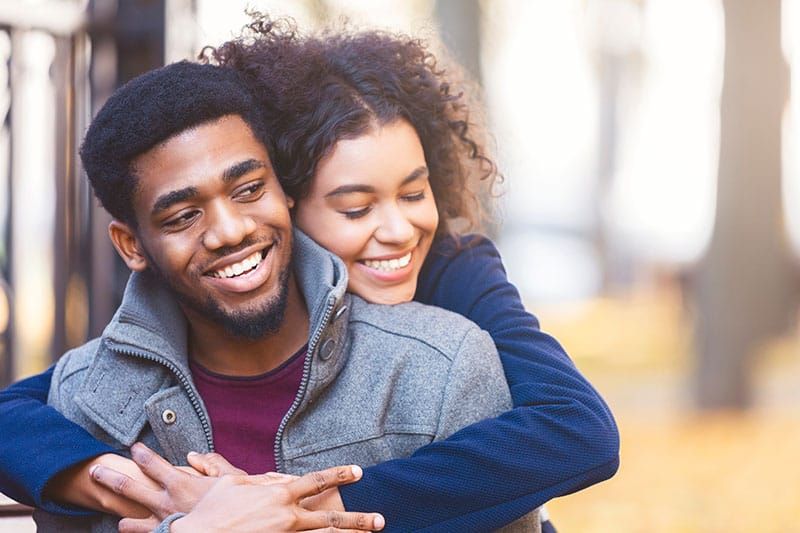 Adorável jovem casal negro abraçando enquanto data no parque de outono, copie o espaço