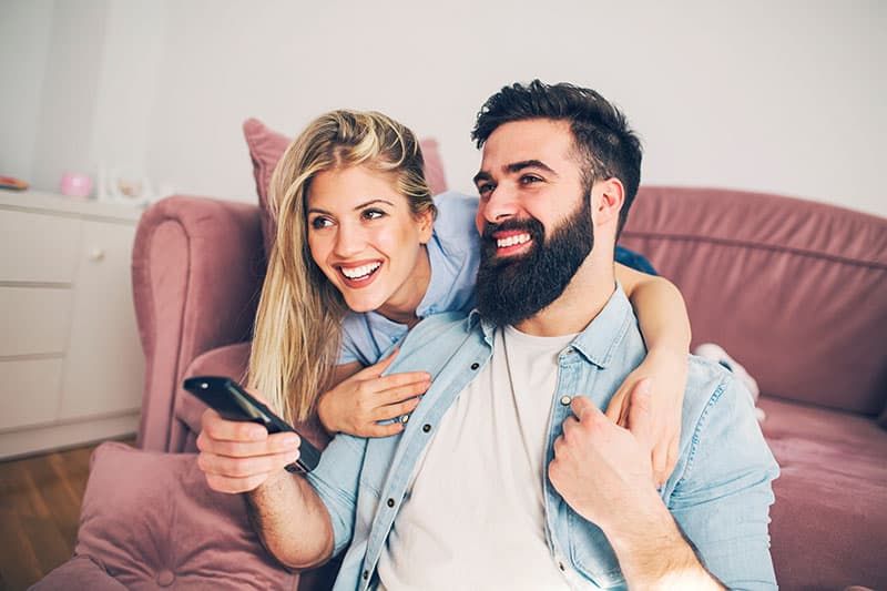 Moderno jovem casal feliz desfrutando em casa e assistindo TV