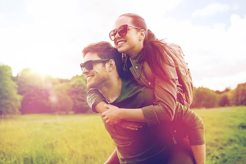 viagens, caminhadas, mochila, turismo e conceito de pessoas - casal feliz em óculos de sol com mochilas se divertindo
