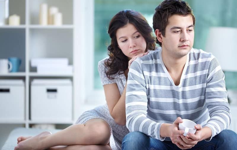 امرأة تعزي الرجل الغاضب جالسًا في غرفة المعيشة