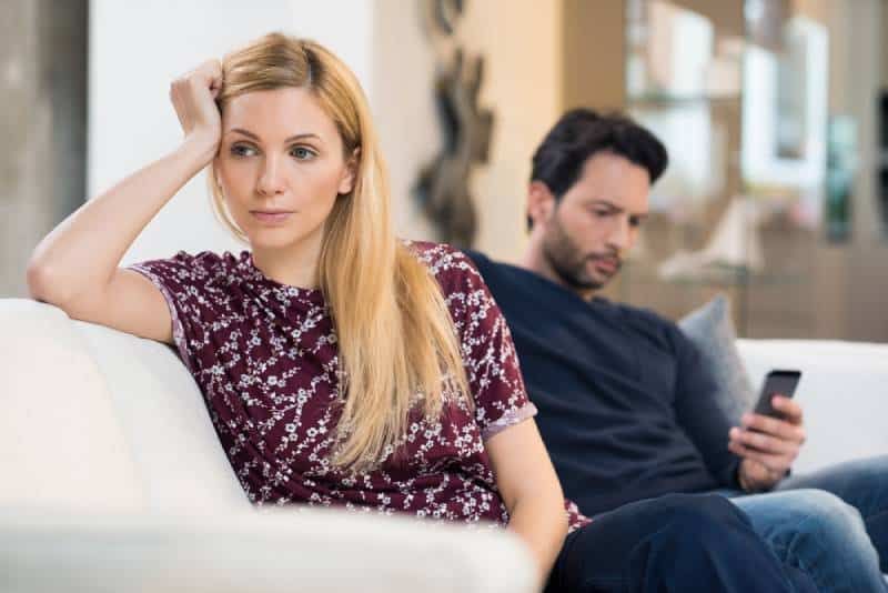 νεαρή κοπέλα που βαριέται ενώ ο φίλος της είναι στο τηλέφωνο