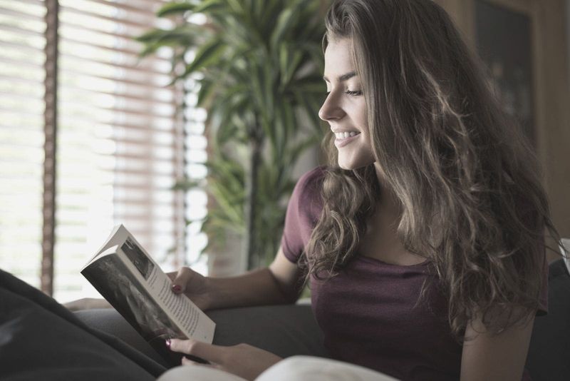 žena koja čita knjigu i smiješi se dok se opušta i čita knjigu