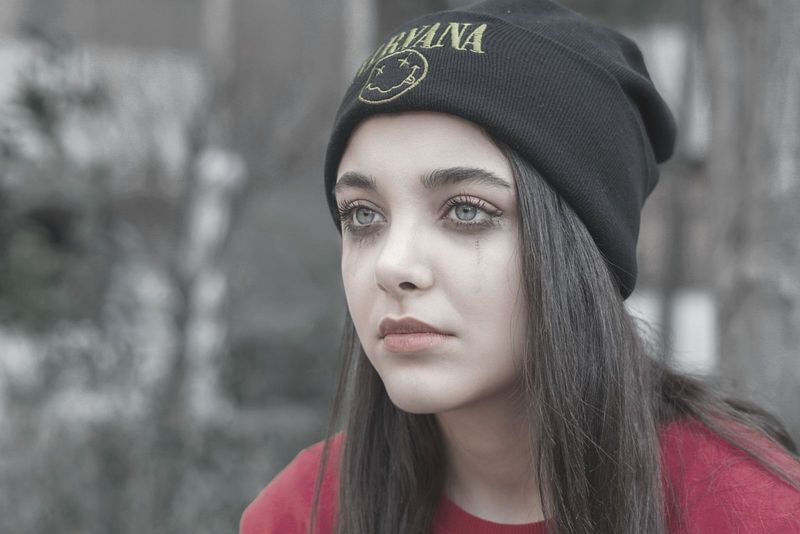 žena u crnoj pletenoj kapici plače i spušta crnu šminku