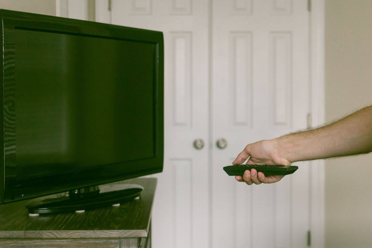 Imagem recortada de homem com controle remoto na frente da TV