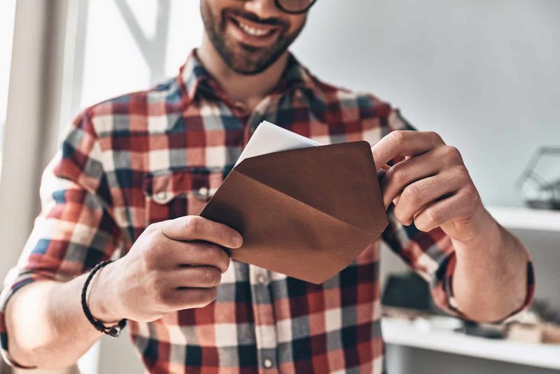 een lachende man opent een envelop met een brief