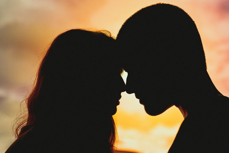 người đàn ông và phụ nữ sắp hôn nhau trong khi mặt trời lặn