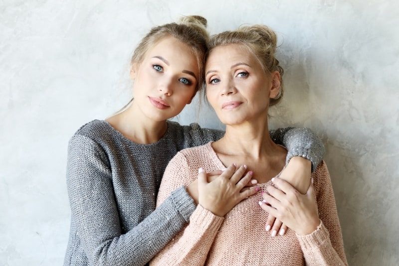 matka a dcéra sa objímajú, keď stoja pri stene