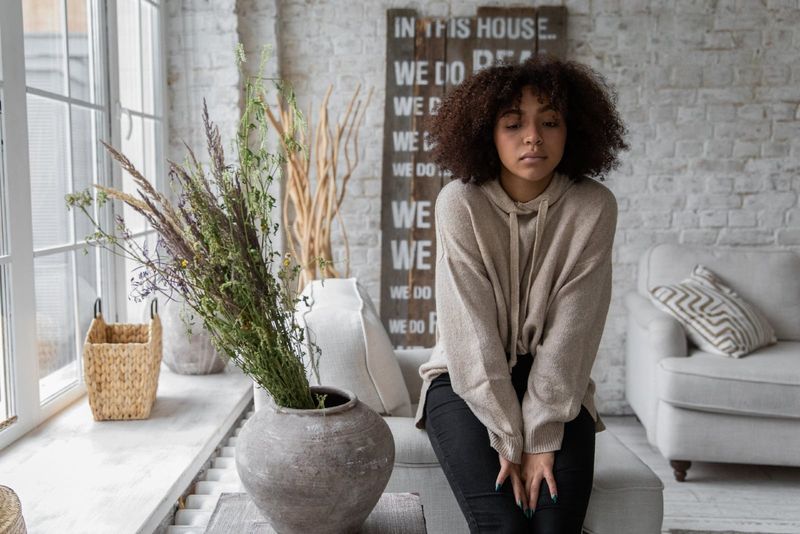 mulher com cabelo encaracolado sentada perto de vaso com flores