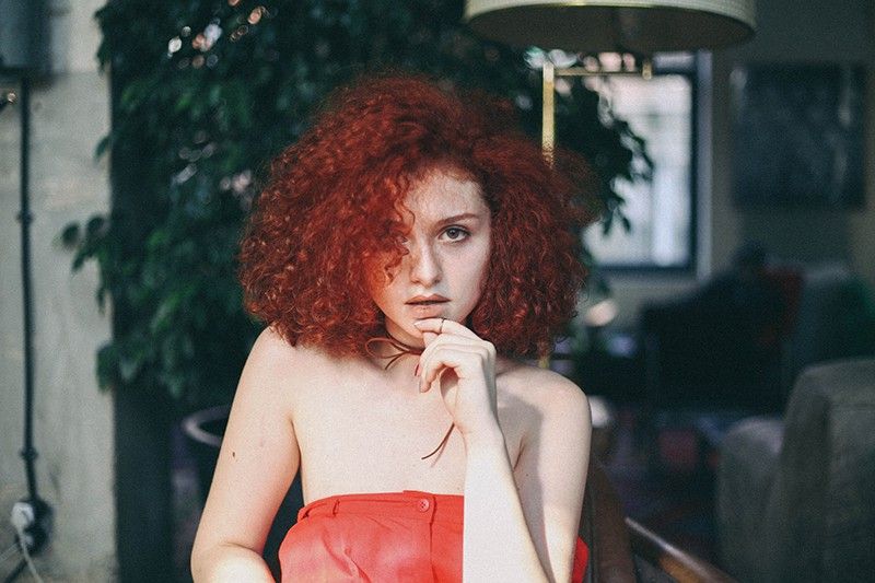 žena u narančastom top od tube dodirujući bradu