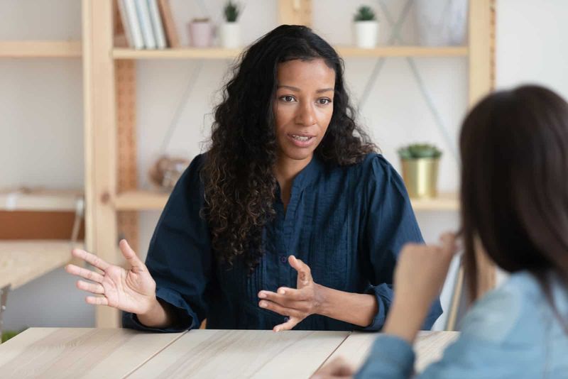 Zwei Frauen sitzen an einem Tisch und unterhalten sich