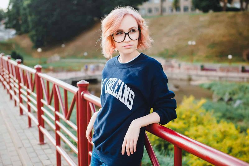 zamišljena žena stoji naslonjena na most i skreće pogled