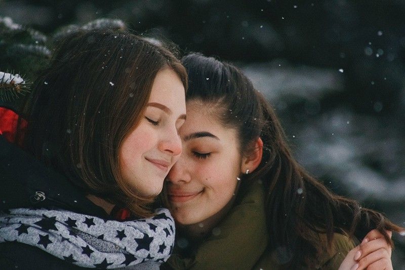 două femei cu ochii închiși îmbrățișându-se