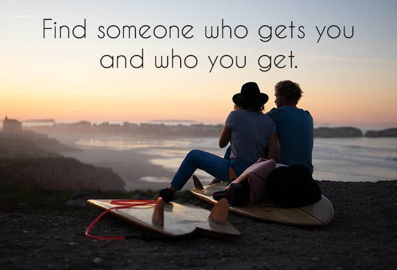 Młoda para siedzi na plaży oglądając zachód słońca