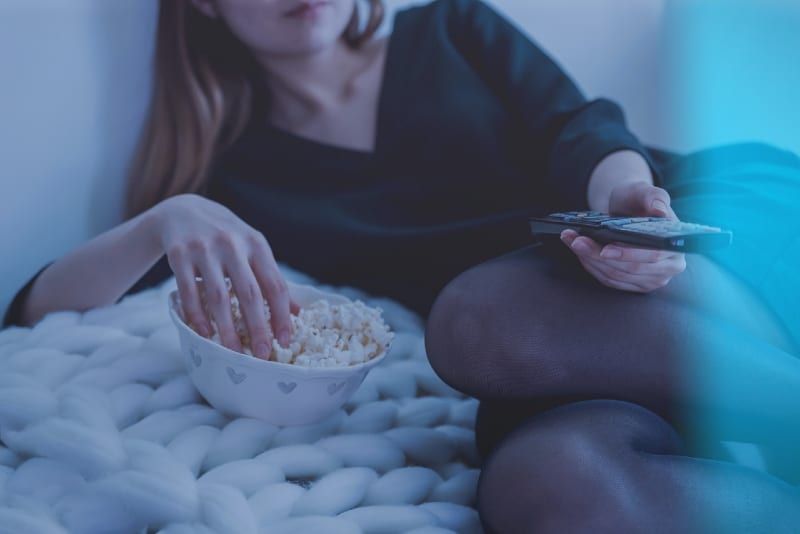 người phụ nữ cầm điều khiển từ xa trong khi ăn bỏng ngô