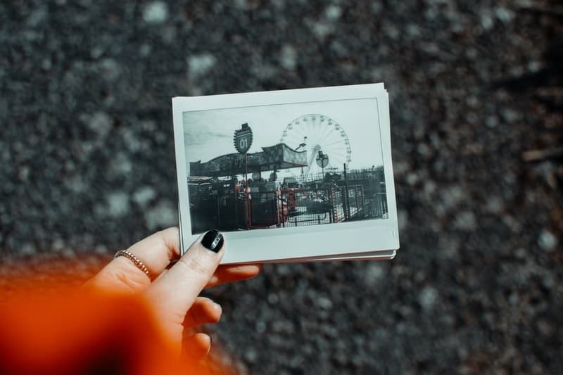 kobieta trzymająca polaroid zdjęcie przyciętego zabawnego parku